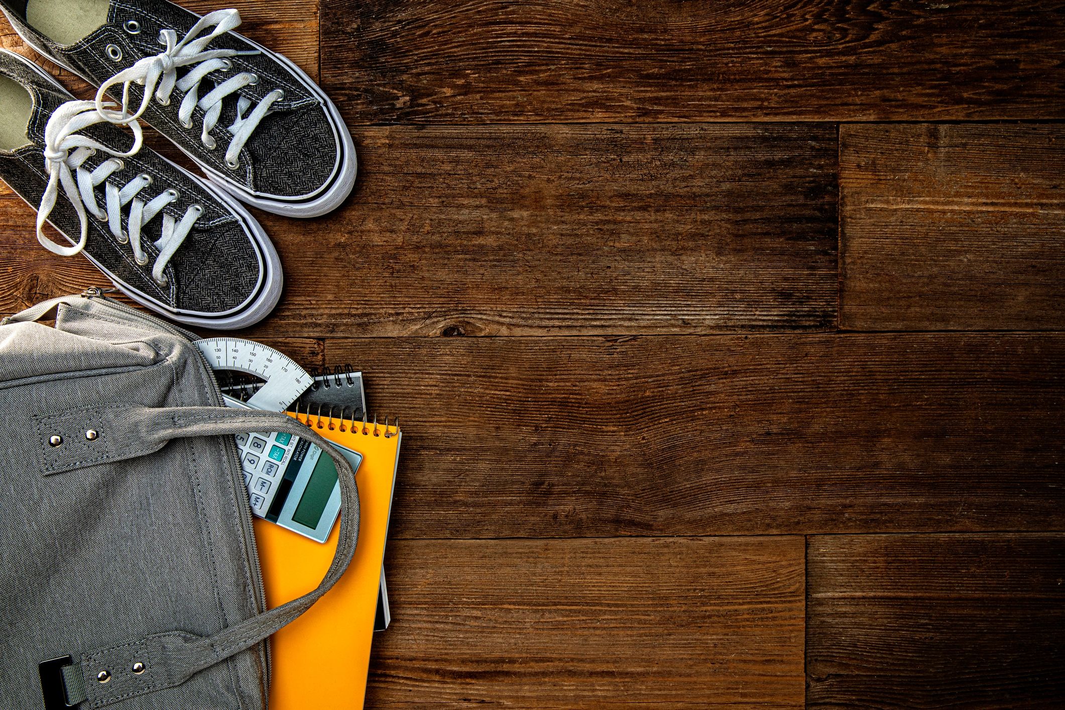 Backpack and sneakers on wooden background