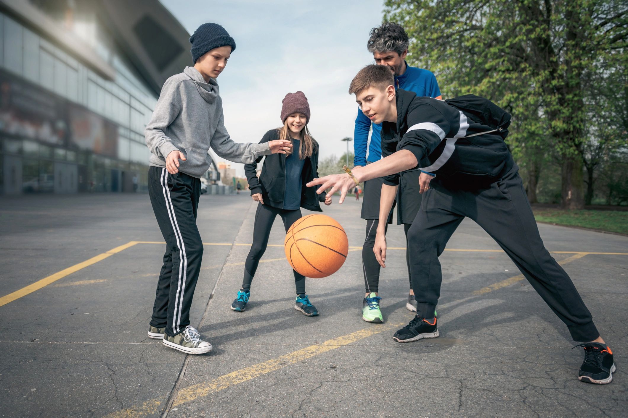 Parent playing basketball with kids outdoors